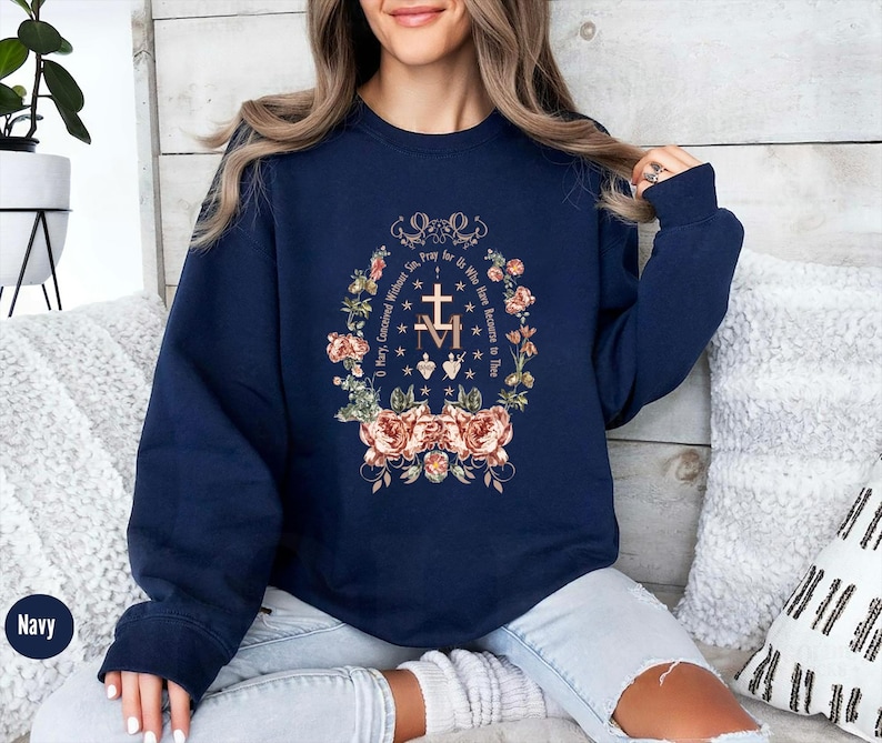 Puede incluir: Sudadera azul marino con un dise&ntilde;o floral y el texto "Oh Mar&iacute;a, concebida sin pecado, ruega por nosotros que recurrimos a ti" en letras doradas.