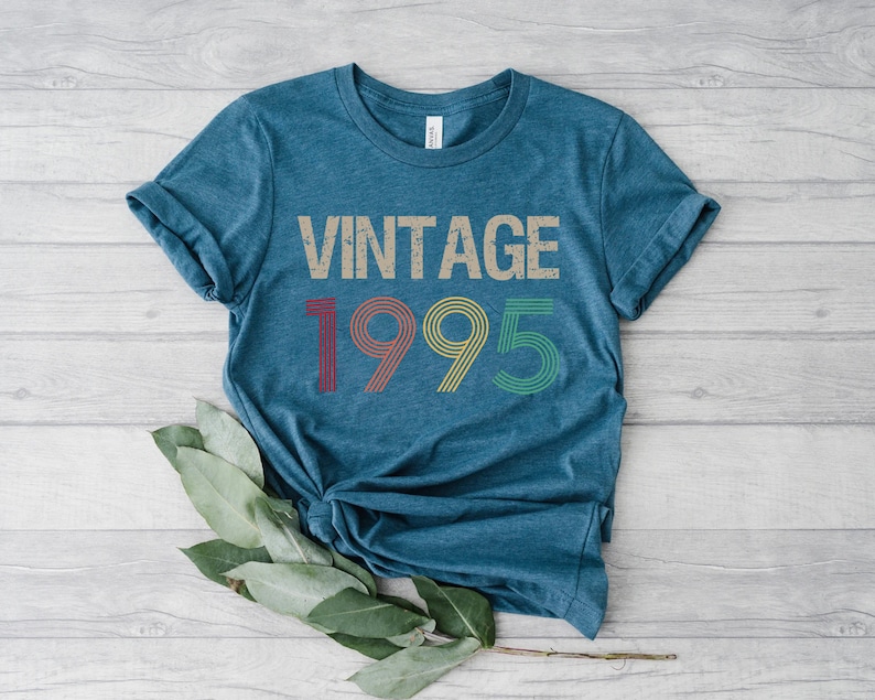 May include: A teal blue t-shirt with the text "Vintage 1995" in a retro font with colorful accents.