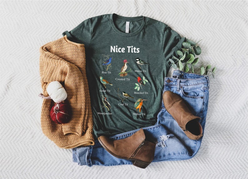 May include: A green t-shirt with the text "Nice Tits" and illustrations of different types of birds with their names below each bird. The birds include a blue tit, crested tit, great tit, willow tit, coal tit, bearded tit, woodpecker, and matsu tit.