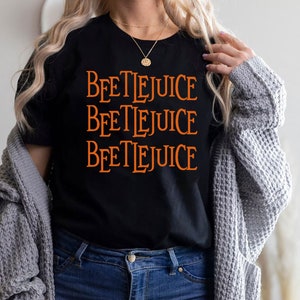 May include: A black t-shirt with the words "Beetlejuice" repeated three times in orange text.