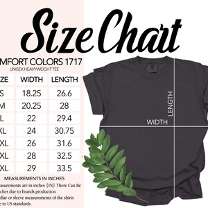 Puede incluir: Una camiseta unisex Comfort Colors gris oscuro con una tabla de tallas. La tabla enumera las tallas S a 4XL, con medidas de ancho y largo en pulgadas. Una ramita de hojas verdes est&aacute; en la esquina inferior izquierda.