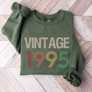May include: A green sweatshirt with the text "Vintage 1995" in a retro font with red, yellow, and green stripes.