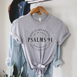 May include: Gray t-shirt with a black circle graphic that says "God is my refuge and my fortress, Psalms 91, I will find shelter under his wings".