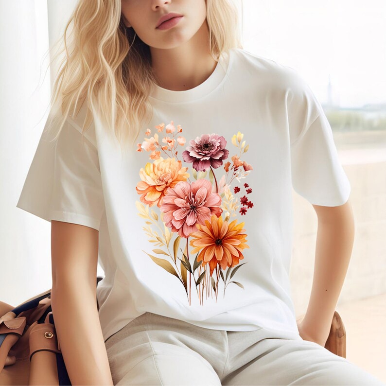 May include: White t-shirt with a floral print featuring a bouquet of orange, pink, and burgundy flowers.