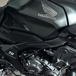 May include: Close-up of a black motorcycle with a Honda logo on the gas tank. The motorcycle has a 70 emblem on the side.