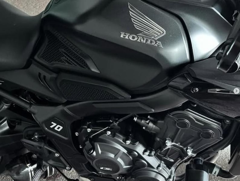 May include: Close-up of a black motorcycle with a Honda logo on the gas tank. The motorcycle has a 70 emblem on the side.