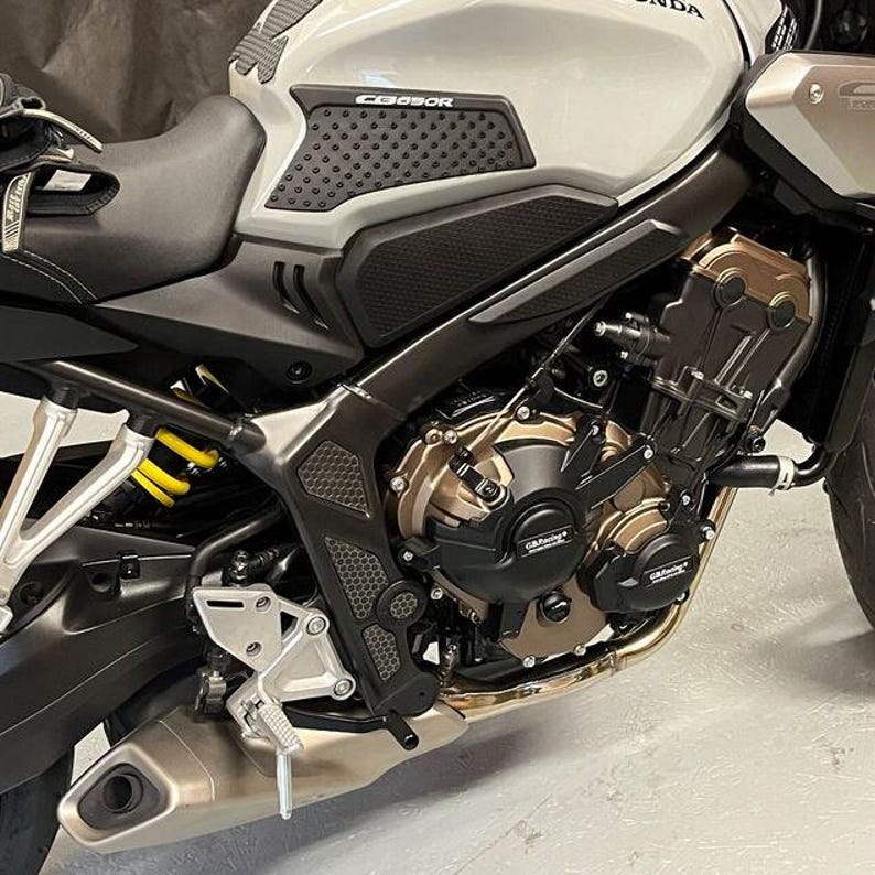 May include: Close-up of a black motorcycle with a gray gas tank and black engine guards. The motorcycle has a black seat and a black exhaust pipe. The gas tank has a black sticker with the word "CB650R" on it.