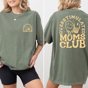 a woman wearing a green tshirt with a yellow mom's club logo