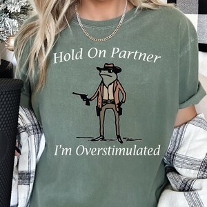 a woman wearing a t - shirt that says hold on partner i'm overs