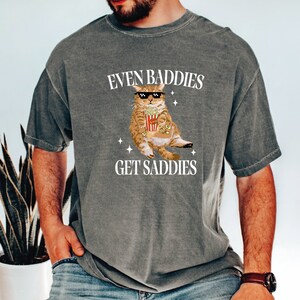a man wearing a t - shirt that says even baddes get saddles