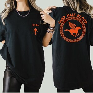a woman wearing a black t - shirt with an orange horse on it
