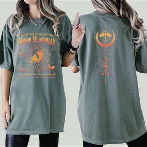 a woman wearing a green shirt with an orange design on it