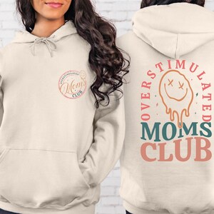 a woman wearing a hoodie with the words mother's club written on it