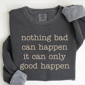 A gray sweatshirt with the text "nothing bad can happen it can only good happen" printed on it.