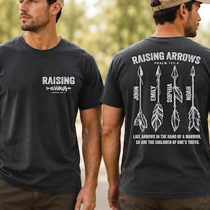 May include: A black short-sleeved t-shirt featuring white text on the front that reads Raising Arrows Psalm 127:4. The back displays four arrow illustrations with the names John, Emily, Sophia, and Noah, plus the text Raising Arrows Psalm 127:4.