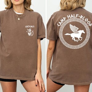 a woman wearing a brown shirt with a white horse on it