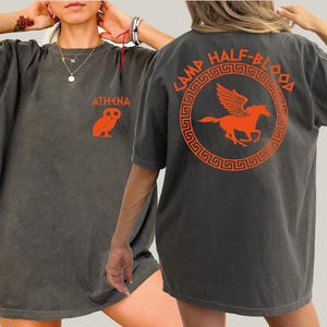 a woman wearing a gray shirt with an orange horse on it