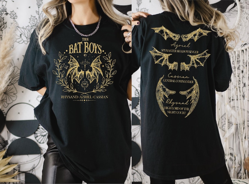 a woman wearing a bat boys t - shirt in front of a wall