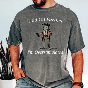 a man wearing a t - shirt that says hold on partner i'm over