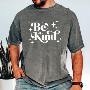 a man with a beard wearing a be kind t - shirt