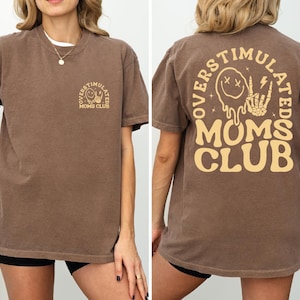 a woman wearing a brown tshirt with a mom's club on it