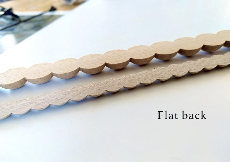 Two strips of unfinished wood trim with a scalloped bead border and flat back