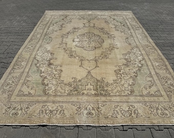 May include: A vintage rug with a beige background and a brown floral pattern. The rug has a faded look and a distressed texture.