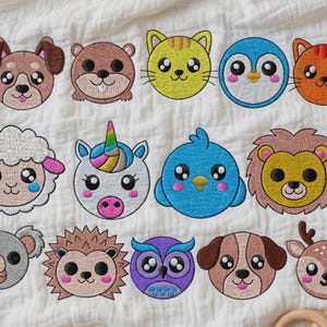 Peut inclure: Une collection de vingt et un écussons brodés d'animaux disposés sur un tissu blanc. Les motifs incluent un rhinocéros, un chien, un castor, un chat, un pingouin, un chat orange, un ours polaire, un hippopotame, un mouton, une licorne, un oiseau bleu, un lion, un taureau, une panthère, un koala, un hérisson, un hibou, un chien, un cerf et un loup.