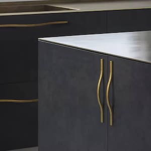 May include: Close-up of dark gray cabinetry with brass-colored hardware. The cabinet doors have wavy, vertical handles. The countertop is a light gray color. The overall design is modern and minimalist.