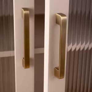 Puede incluir: Primer plano de una puerta de armario blanca con un tirador vertical de color lat&oacute;n antiguo. La puerta tiene un panel de vidrio texturizado y acanalado. El tirador es rectangular con un agarre curvado.
