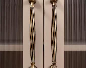 May include: Two antique-style cabinet door handles. The handles are made of brass-colored metal with a twisted, grooved design. Each handle has a rounded top and bottom, and they are mounted on a light-colored cabinet door.