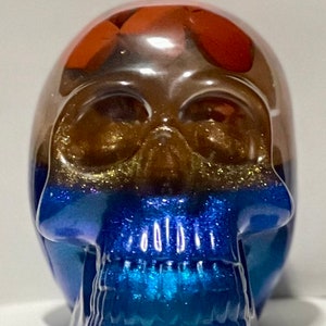 Detailed skull made with epoxy resin. Multi colored with resin dyes and mica. 4 x 3.42 x 2.61 inches.