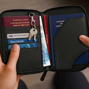 Könnte beinhalten: Schwarzes Reise-Portemonnaie mit Reißverschluss, das einen britischen Führerschein, eine Visa-Karte und einen britischen Reisepass enthält. Enthält eine Bordkarte, Bargeld und Schlüssel.