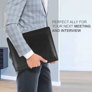May include: A black leather portfolio folder with a silver clasp. The folder is being held by a person wearing a light blue plaid blazer and black trousers. The text "PERFECT ALLY FOR YOUR NEXT MEETING AND INTERVIEW" is visible in the image.