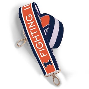 May include: A navy blue and orange shoulder strap with the text "FIGHTING ILLINI" in white. The strap has gold-colored metal clasps and a white and navy blue striped pattern on the back.