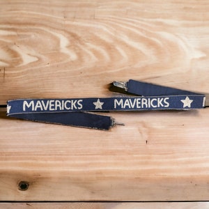 May include: A blue and gold fabric wristband with the word "MAVERICKS" and a gold star on each side.