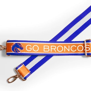 May include: Blue and orange striped strap with a white "GO BRONCOS" logo and a horse head graphic. The strap has gold metal clasps.