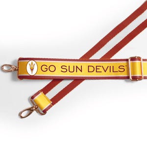 May include: A maroon and gold adjustable bag strap featuring the text GO SUN DEVILS and a trident logo. The strap includes metallic gold-toned swivel lobster clasps and a sliding buckle for length adjustment, constructed from durable woven fabric.