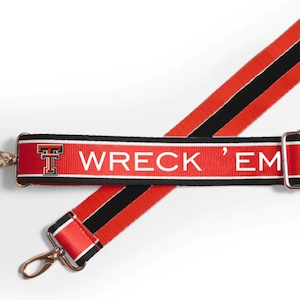 May include: Red and black adjustable strap with a white stripe and the text "Wreck 'Em" and a black and orange "T" logo.