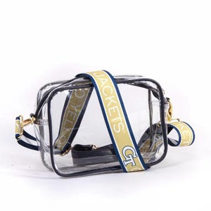 May include: Clear plastic crossbody bag with a gold and navy blue adjustable strap that says "GT Jackets".
