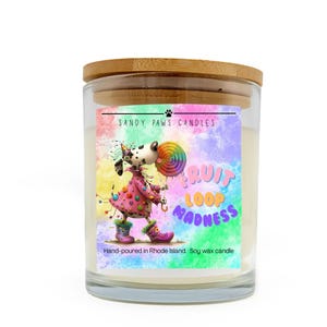 May include: A glass candle jar with a wooden lid. The label features a cartoon dog holding a lollipop, with the text "FRUIT LOOP MADNESS." The candle is hand-poured in Rhode Island and made with soy wax.