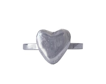 Könnte beinhalten: Ein silberner Ring mit einem herzförmigen Design. Das Herz ist erhaben und hat eine glatte, abgerundete Oberfläche.