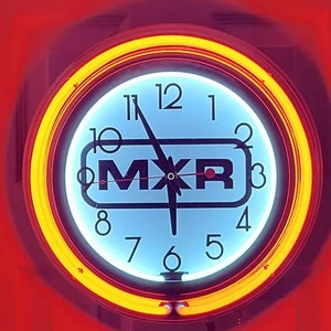 Puede incluir: Un reloj de neón blanco con un anillo de neón amarillo alrededor del borde. La esfera del reloj tiene números y manecillas negros, y la palabra "MXR" en letras negras. El reloj está configurado a las 10:50.