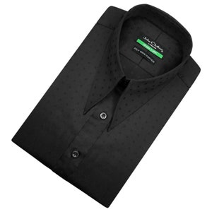 Puede incluir: Una camisa negra de vestir con cuello extendido y un pequeño patrón repetitivo. La camisa está hecha de 100% algodón y tiene una etiqueta que dice "John Clothes London Green Label 2PLY 100% Algodón."