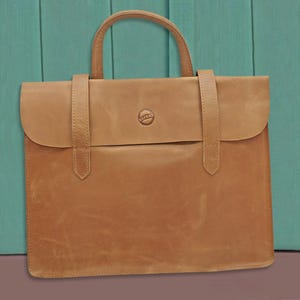 May include: A tan leather briefcase with a single flap and a small circular logo. The bag has two handles and a strap.