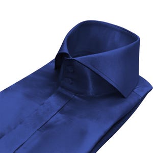 Puede incluir: Camisa azul marino doblada. Presenta un cuello clásico y una tapeta abotonada. La tela tiene un brillo sutil, posiblemente seda o satén. La camisa está cuidadosamente doblada, mostrando su diseño.