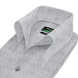 Può includere: Una camicia bianca con un piccolo motivo geometrico. Il colletto è ripiegato verso il basso e la camicia ha una chiusura con bottoni. L'etichetta sul colletto riporta "John Charles London" e "Green 100% Cotton".