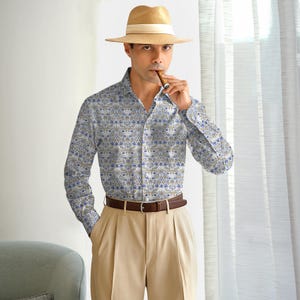 May include: A long-sleeved button-down shirt with a floral pattern in blue and gold on a white background. The shirt is paired with khaki pants and a brown belt. A straw hat with a white band completes the look.