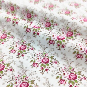 May include: White fabric with a repeating floral pattern. The design features clusters of pink roses and smaller red flowers with green leaves, set against a backdrop of tiny, scattered white blossoms and brown stems.