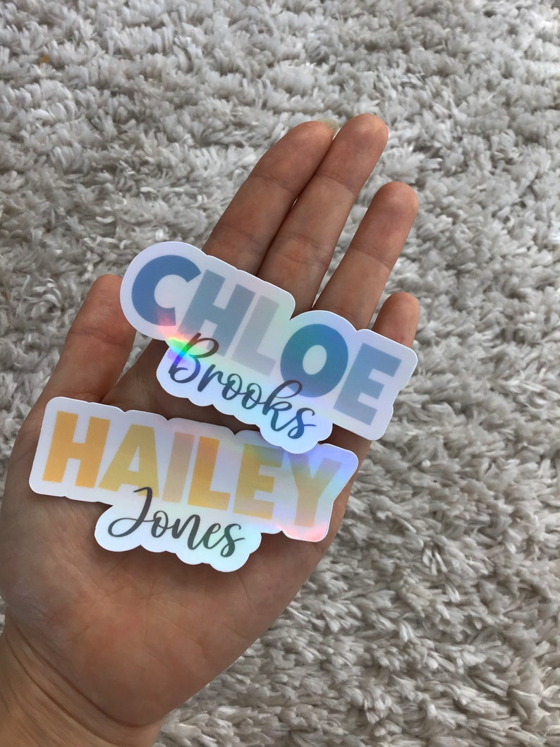 May include: Two iridescent holographic stickers with names. The top sticker is blue and says "Chloe Brooks". The bottom sticker is yellow and says "Hailey Jones".